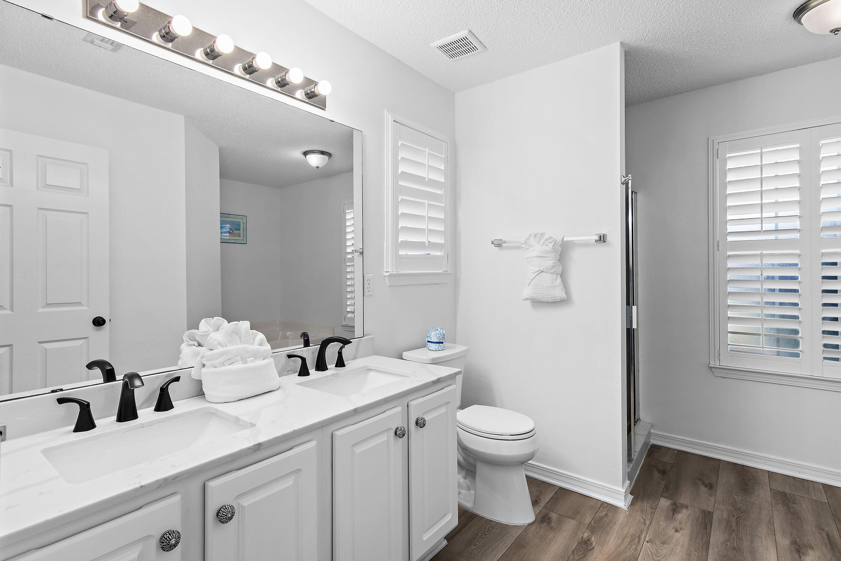 A bathroom with a white vanity, a sink, a toilet, and a shower.