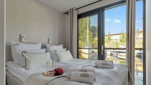 A hotel room with a large bed, a view of the outside, and a window with curtains.