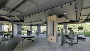 A gym with exercise equipment, a bench, and a wall-mounted machine labeled 'XMor.' - Porto 42 | 2 Bedrooms | Gym | Balcony | Parking (Gdańsk)