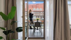 A room with a view of a building with a red roof, a potted plant, and a chair. - Waterlane E3A | Spa, Pool & Gym | River View (Gdańsk)