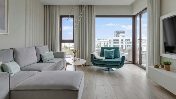 Un saló modern amb un sofà gris, un butac armchair teal i una televisió de pantalla plana a la paret.