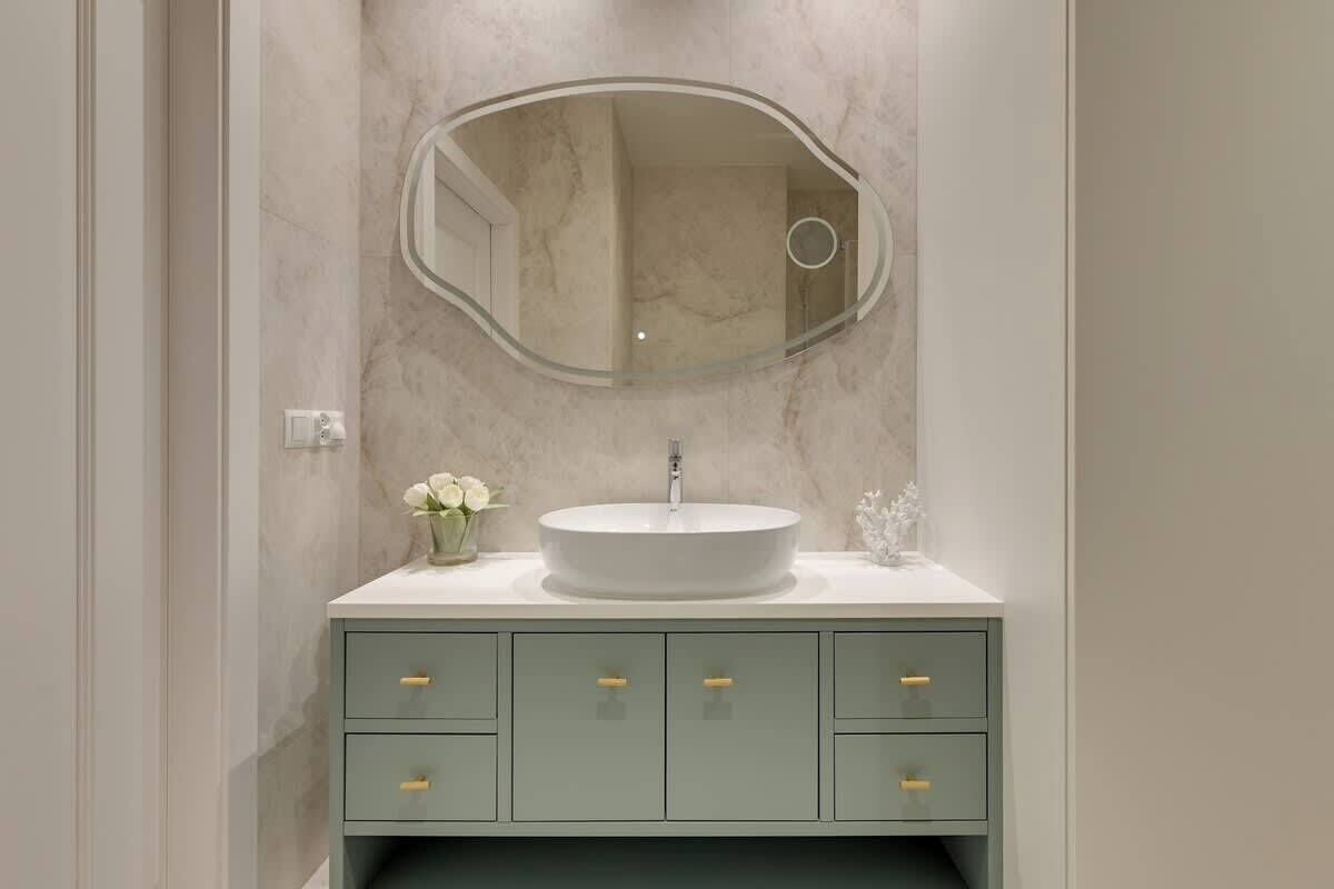 A bathroom with a round sink, a mirror, and a cabinet with drawers.