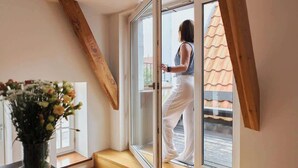 Ein Zimmer mit einer Holztreppe, einer Schiebetür und einem Blumenstrauß in einer Vase.