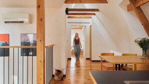 Ein modernes Interieur mit einer Holztreppe, einem Essbereich und einem Flur, der zu einem weiteren Zimmer führt.