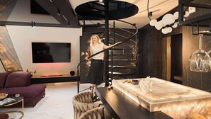 Et moderne interiør med en spiraltrappe, et fladskærms-tv, et marmorbord og en sofa.