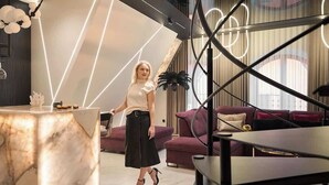 Et moderne interiør med et marmorbord, en sofa og et geometrisk loftdesign.
