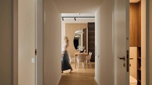 Un pasillo con comedor, una puerta de madera y un inodoro a la vista.