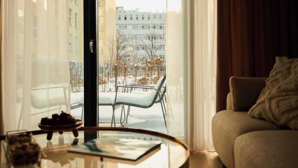 Una sala de estar moderna con una mesa de vidrio, un sofá y vistas a un paisaje nevado a través de un amplio ventanal.