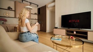 Una sala de estar con sofá, mesa de centro y un televisor que muestra 'NETFLIX'.