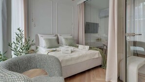 A modern bedroom with a bed, bedside tables, a chair, and a view through a glass door.