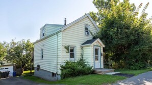 A single-story house with a front porch, a garage, and a small shed.