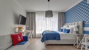 Quarto de hotel moderno com cama, sofá, escrivaninha e televisão.