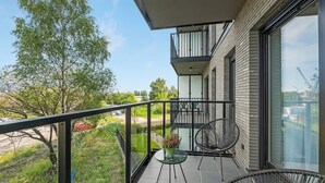 Ein Balkon mit Blick auf Grünflächen und ein Gebäude.