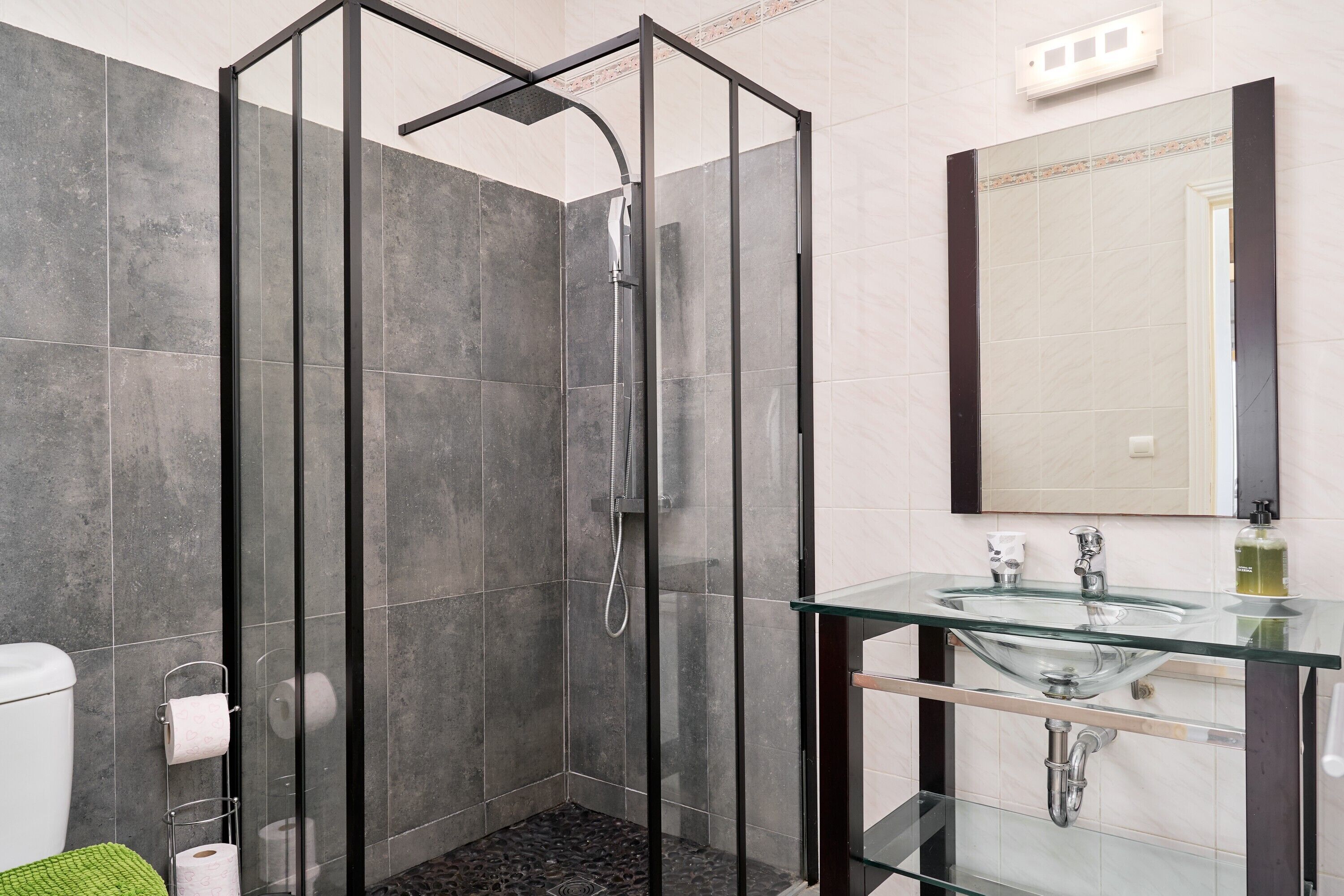 A modern bathroom with a glass shower enclosure, a glass sink, and a large mirror.