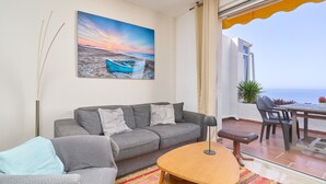 Una sala de estar con un sofá, una mesa y un cuadro de una playa.