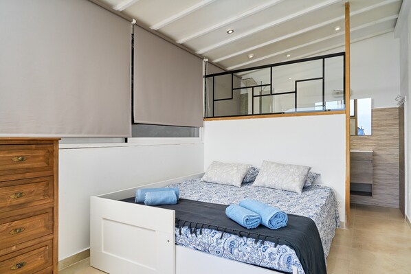 A bedroom with a bed, a wooden dresser, a window with blinds, and a mirror. - Holiday Home 'Trino' with Sea Views, Wi-Fi and Air Conditioning (Almuñécar)