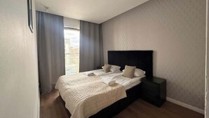 Ein Schlafzimmer mit einem großen Bett, einem Nachttisch und einem Fenster mit Vorhängen.