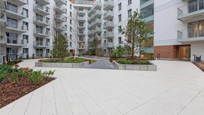 A multi-story residential building with balconies, a central courtyard with planters, and a brick section on one side. - Żurawie A31 | Shipyard | Foodhall Montownia (Gdańsk)