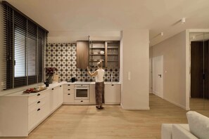A modern kitchen with a built-in oven, a wine glass, and a fruit bowl on the counter. - Granaria C105 | Best Location (Gdańsk)
