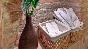 En mur af mursten med en vase med grønne planter og en kurv med håndklæder.