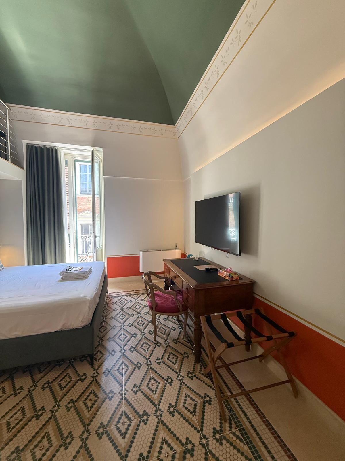 Een hotelkamer met een bed, een bureau, een stoel, een televisietoestel en een vloer met patroon.