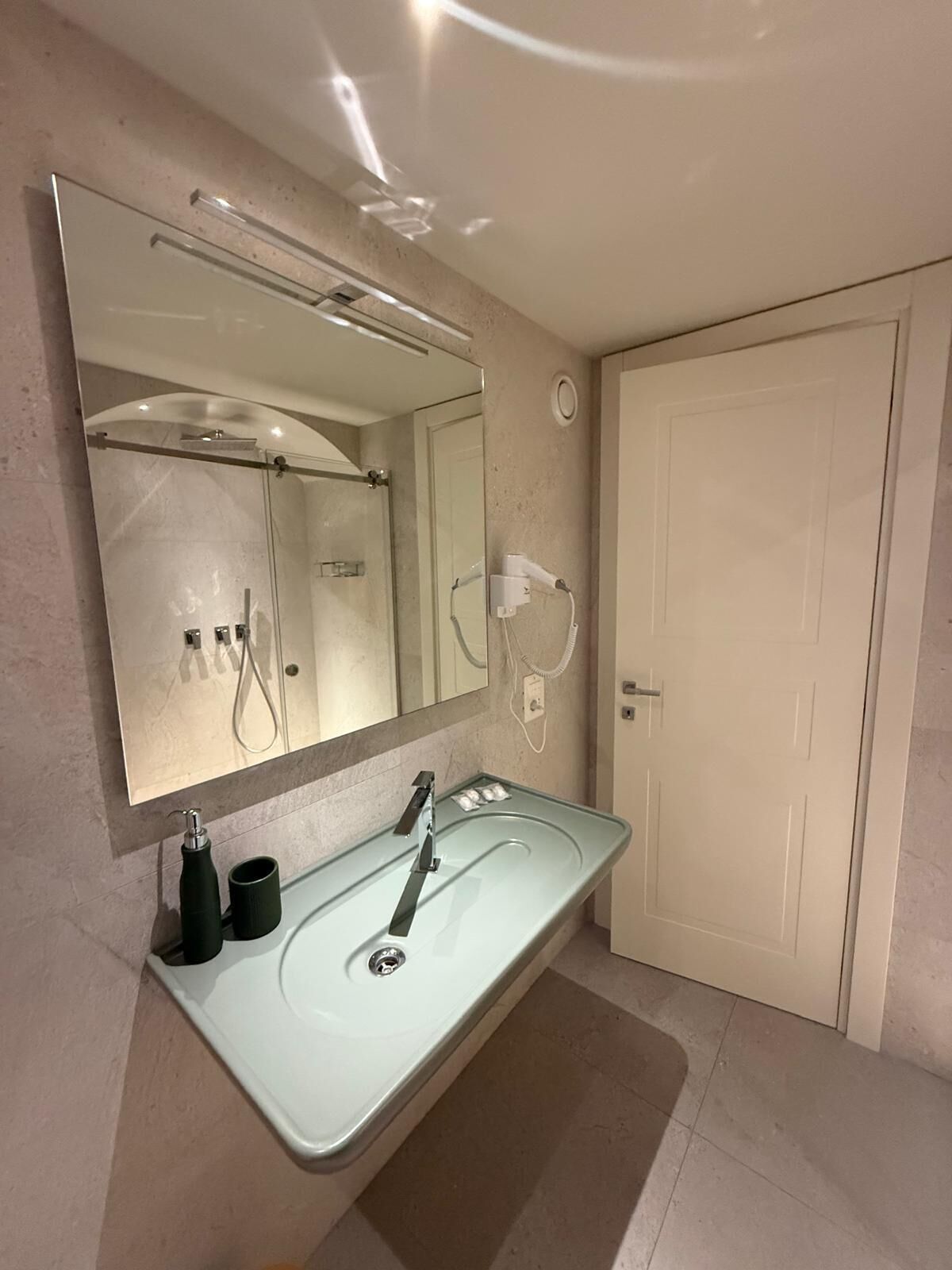 Un baño moderno con un espejo grande, lavamanos doble y ducha.