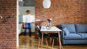 Un espace de vie moderne avec un mur en briques, une table à manger avec des chaises et un canapé bleu.