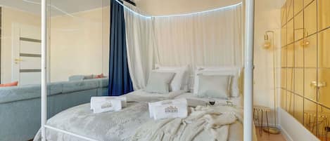 A four-poster bed with a canopy, a sofa, and a small round table.