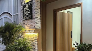 A hotel entrance with a stone facade, a sign reading 'An Nhen 7,' and potted plants. - Bliss Home (Da Nang)