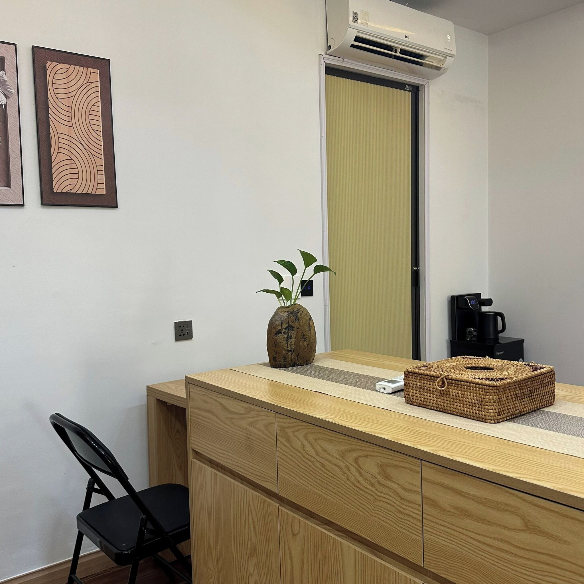 A small kitchenette with a coffee maker, a wicker basket, and a potted plant on the counter.