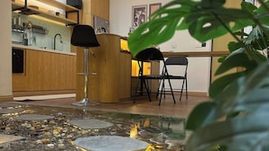 A reception area with a water feature, wooden cabinets, and a desk with chairs. - Bliss Home (Da Nang)