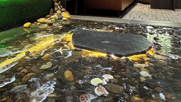 A living room with a sofa, a coffee table, and a decorative water feature. - Bliss Home (Da Nang)