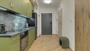 Een kleine keuken met groene kastjes, een marmeren aanrechtblad en een houten vloer.