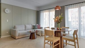 A modern living room with a sofa, round dining table, chairs, and a pendant light. - Granaria B503 | 2 Balconies (Gdańsk)