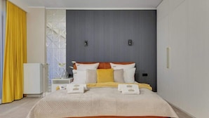Una camera d'albergo moderna con un letto grande, un comodino e una finestra con tende.