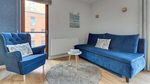 Una sala de estar moderna con un sofá azul, un sillón azul y una mesita redonda.
