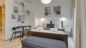 Ein modernes Hotelzimmer mit Bett, Nachttischen, Schreibtisch, Sesseln und an der Wand befestigter Kunst.