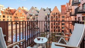 Ein Balkon mit Tisch und Stühlen, der auf einen Innenhof mit Gebäuden blickt.