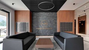 En modern entréhall med två svarta soffor, ett soffbord i trä och en vägg i marmor med en logotyp.