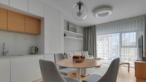 Un espace de vie moderne comprenant une cuisine, un coin repas et une grande fenêtre donnant sur la ville.
