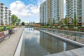 A residential area with modern apartment buildings, a central water feature, and a pedestrian walkway. - Letnica 2 with Terrace | Perfect Stay (Gdańsk)
