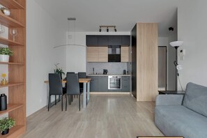 A modern kitchen with a dining area, a sofa, and a lamp. - Letnica 2 with Terrace | Perfect Stay (Gdańsk)