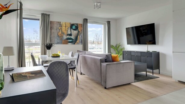 A modern living room with a sofa, dining table, and TV. - Przystań Letnica 39 | Comfortable Stay & Parking (Gdańsk)