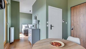Une chambre moderne avec une table à manger ronde, un lit avec une table de chevet, une porte blanche et un radiateur.