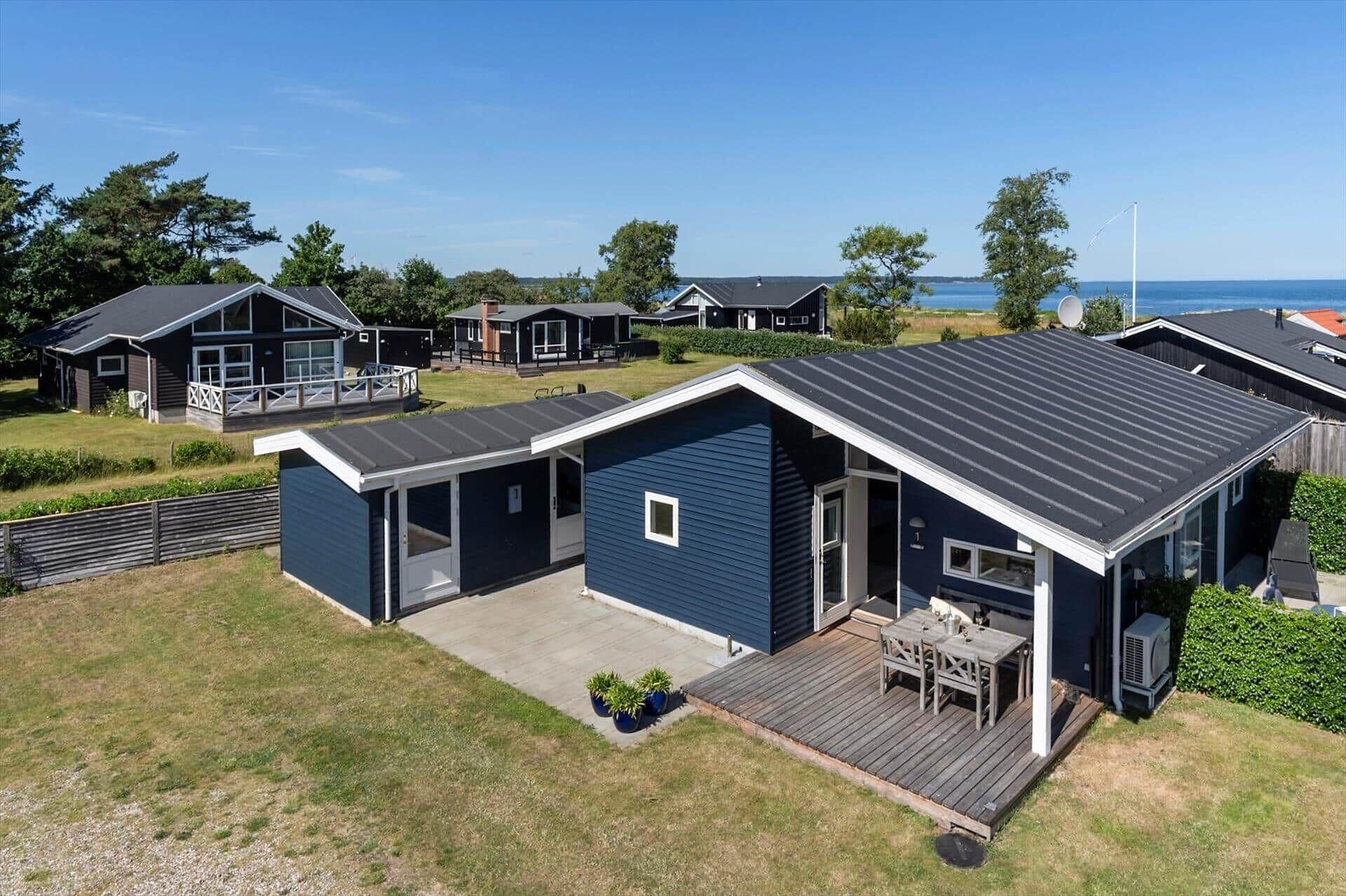 A modern vacation home with a deck, a covered patio, and a view of the sea.