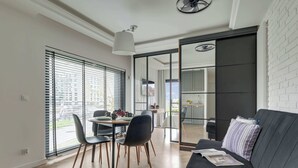 A modern living space with a dining area, a sofa, and a sliding glass door leading to a kitchen.