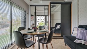 A modern dining area with a round table, chairs, and a view through large windows.
