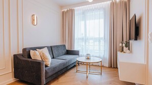 En moderne stue med en mørkegrå sofa, et rundt sofabord og et fladskærms-tv monteret på væggen.