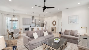 A modern living room with a sofa, coffee table, and dining area. - Crisp Ocean Breeze | Private Pool | Walk to Beach | Golf Cart(LSV) (Santa Rosa Beach)