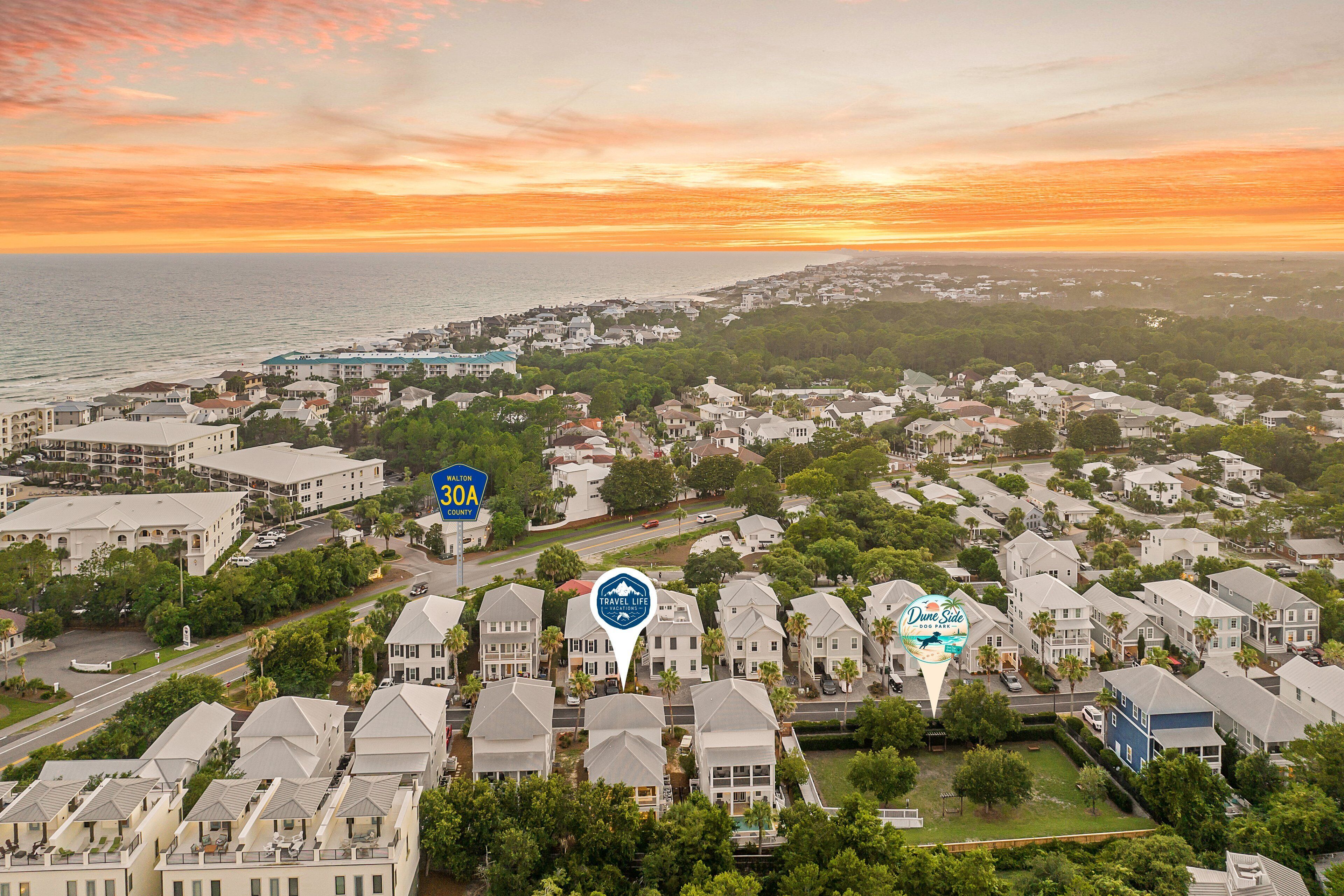 A coastal residential area with multiple-story houses, a marina, and a sunset view.
